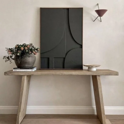 Tableau contemporain 3D fait main avec cadre en noyer accroché sur un mur blanc avec une lamp dans un salon avec console en bois moderne et vase d'argile gris desssus.