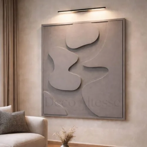 Tableau abstrait 3D en relief aux formes organiques gris clair, éclairé par un spot, dans un salon moderne et épuré.