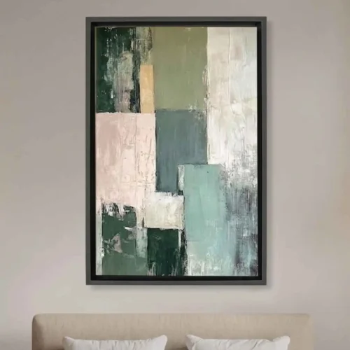 Tableau abstrait color fusion moderne aux tons vert sauge, beige et rose poudré avec un cadre noir flottant suspendu au-dessus d'un lit.